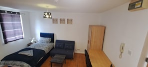 Ein Schlafzimmer mit Bett, Sofa, Schreibtisch, Kleiderschrank und einem Wandtelefon.