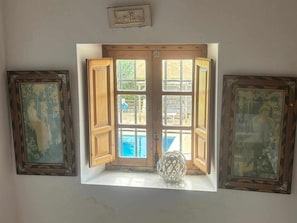 Ein Zimmer mit Fenster, zwei gerahmte Bilder an beiden Seiten und ein kleines dekoratives Objekt auf der Fensterbank.