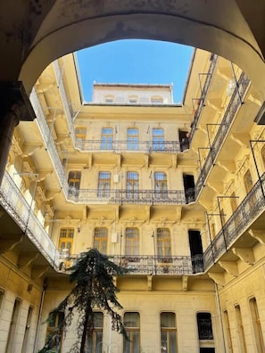 Un immeuble à plusieurs étages doté de balcons, d’une cour intérieure et surplombant un ciel dégagé.