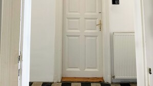 A white door with a brass handle, a black number plate, and a radiator to the right.