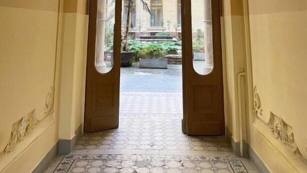 Un pasillo con un arco que da a un patio con balcón.