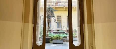 A corridor with an arched doorway leading to a courtyard with a balcony.
