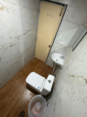 A small bathroom with a toilet, sink, and a door labeled 'Lounge.'