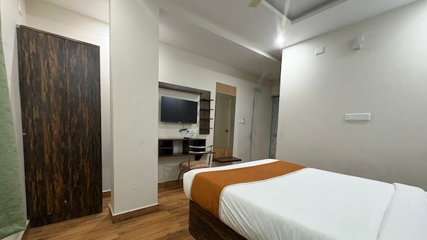 Un dormitorio con cama, escritorio, silla y televisor.