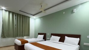 Habitación de hotel con dos camas, ventilador de techo y ventana con cortinas.
