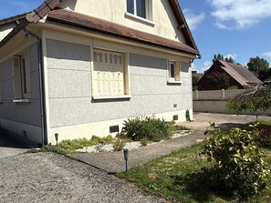 A two-story house with a sloped roof, a window with shutters, and a small garden area with plants and a gravel path. - Renovated studio in quiet area - 2 guests (Villers-sur-Mer)