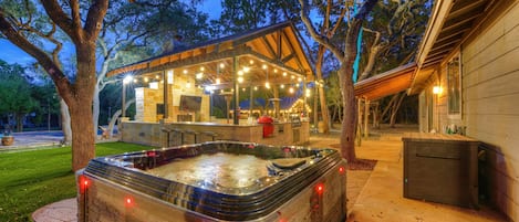A hot tub, outdoor seating area, and a covered structure with string lights.