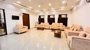 A spacious living room with beige sofas, a coffee table, and a TV mounted on the wall.