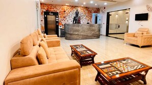 A lobby with a reception desk, a statue, a sofa, and two coffee tables.