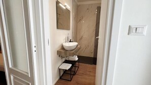 Un baño con un lavamanos blanco, un espejo y un perchero para toallas.