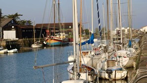 A marina with boats docked, a building with a sign, and a clear sky. - Family house with indoor courtyard - 4 guests (Noirmoutier-en-l'Île)