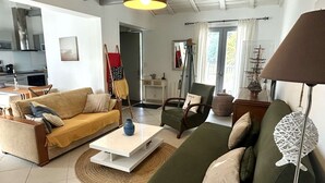 A living room with a sofa, armchair, coffee table, and lamp. - Family house with indoor courtyard - 4 guests (Noirmoutier-en-l'Île)