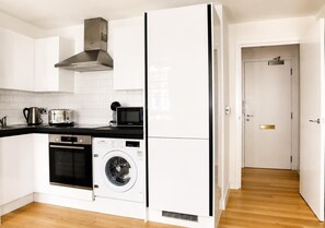 Eine kleine Küche mit Waschmaschine, Backofen und Mikrowelle.
