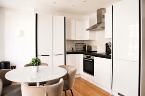 A modern kitchen with white cabinets, a black countertop, and a stainless steel range hood. - Charming 1BR with Balcony in Central Fitzrovia (London)