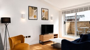 Ein modernes Wohnzimmer mit Fernseher, Sofa und Kunstwerk an der Wand.