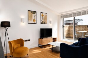 A modern living room with a TV, sofa, and artwork on the wall. - Fitzrovia and West End Residences (London)