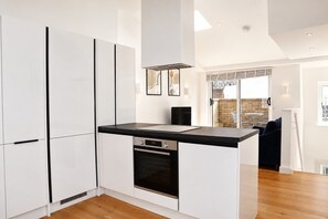 A modern kitchen with white cabinetry, a black countertop, and a built-in oven. - Fitzrovia and West End Residences (London)