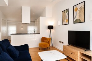 A modern living room with a sofa, a coffee table, a TV, and artwork on the wall. - Fitzrovia and West End Residences (London)