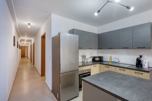Eine moderne Küche mit Edelstahlgeräten, grauen Schränken und einem langen Flur mit Holztüren.