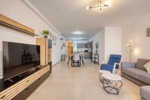 A modern living room with a flat-screen TV, a dining area, and a kitchen in the background. - Bright & luxury apartment with 2 balconies JVEL1-1 (St. Paul’s Bay)
