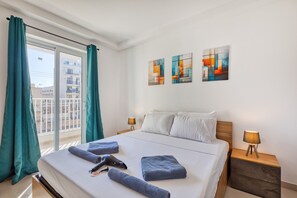 Ein Hotelzimmer mit einem Bett, zwei Nachttischen, einem Vorhangfenster und abstrakter Wandkunst.