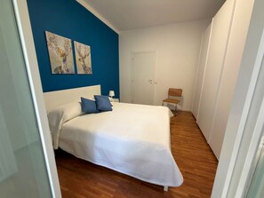 Ein Schlafzimmer mit einem Bett, einem Sessel und zwei Wandbildern.