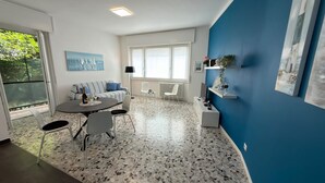 Ein modernes Wohnzimmer mit Essbereich, großen Fenstern und einer blauen Akzentwand.