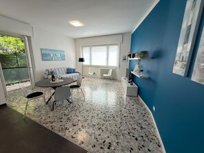 Ein modernes Wohnzimmer mit Essbereich, großen Fenstern und einer blauen Akzentwand.