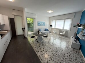 Eine moderne Küche mit Essbereich, einer Couch und einem großen Fenster.