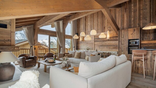 A spacious living area with a sofa, chairs, a coffee table, and a fireplace. There are wooden beams on the ceiling and a view of the outdoors. - Spacious chalet near slopes - 14 guests (Saint-Martin-de-Belleville)