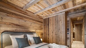 A wooden-paneled bedroom with a bed, pillows, and a rolled towel. - Spacious chalet near slopes - 14 guests (Saint-Martin-de-Belleville)