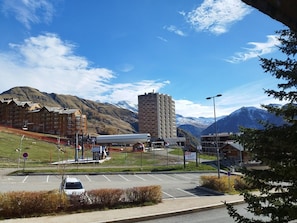 Ein Parkplatz mit einem Gebäude im Hintergrund, einem Gebirgszug und einem klaren Himmel.