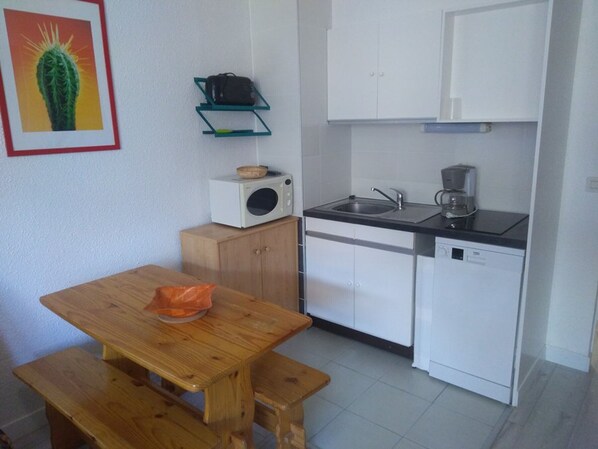 A compact kitchen with a wooden table, a microwave, a sink, and a coffee maker. - Modern studio at the slopes - 4 guests (Orcières Merlette)