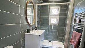 Un baño moderno con ducha, lavamanos e inodoro.