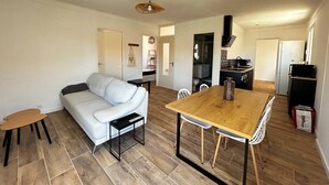Un espacio habitable compacto con sofá, una mesa de comedor, una zona de cocina y un pequeño rincón de estar.