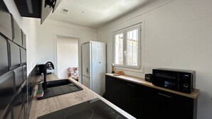Una cocina compacta con estufa negra, microondas y refrigerador.