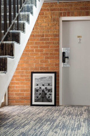 A staircase leading to a room with a brick wall, a door with a lock, and a framed picture on the wall. - Sunlit Courtyard 2BR Apartment Heart Of St Kilda (St Kilda)
