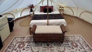 A tent with a bed, a lamp, a small table, and a chair.