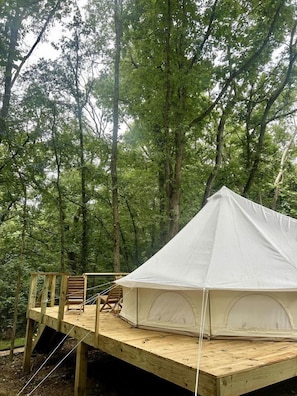 A tent on a wooden platform in a forest.