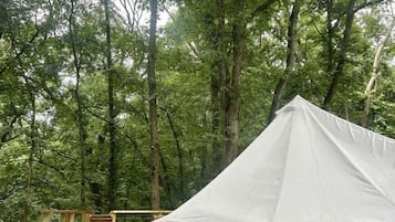 A tent on a wooden platform in a forest.