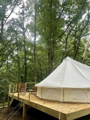 Une tente installée sur une plateforme en bois, au cœur d’une forêt.