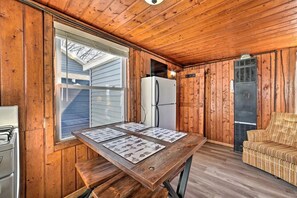 Een houten blokhut interieur met een eettafel, een koelkast en een bank.
