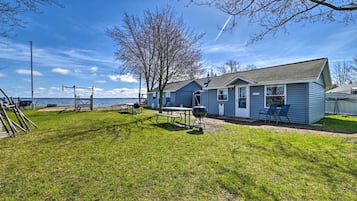 Ein Haus mit Garten, Grill und Blick aufs Wasser.