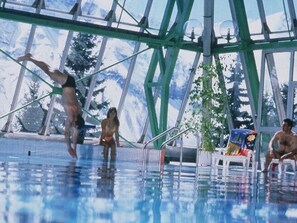 An indoor swimming pool with a glass ceiling, metal railings, and a view of trees outside. - Bright apartment, 6 guests, ski-in ski-out (Orcières Merlette)