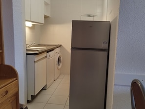 A compact kitchen with a refrigerator, washing machine, and a small countertop with a sink. - Bright apartment, 6 guests, ski-in ski-out (Orcières Merlette)