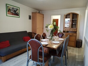 A dining area with a wooden table set for four, surrounded by metal chairs. A wooden cabinet and a kitchen area are visible in the background. - Bright apartment, 6 guests, ski-in ski-out (Orcières Merlette)