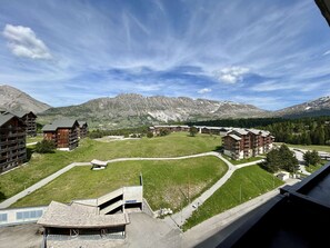 A mountain lodge with multiple wooden buildings, a central grassy area, and a view of snow-capped mountains. - Studio with mountain view - 5 guests (Le Dévoluy)