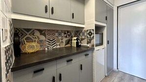 Una cocina moderna con armarios grises, encimera negra y azulejos decorativos en la pared.