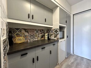Eine moderne Küche mit grauen Schränken, einer schwarzen Arbeitsplatte und einer Rückwand mit Musterfliesen.