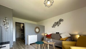 Una sala de estar moderna con un sofá, un sillón amarillo, una mesita y un adorno en la pared.
